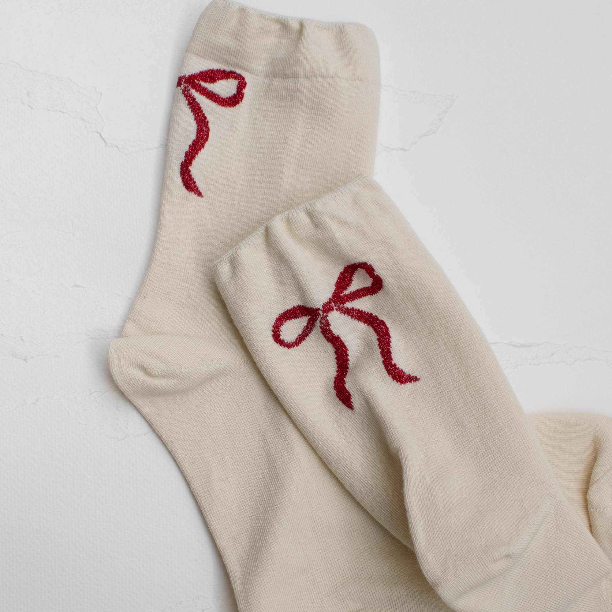 These charming crew socks blend comfort with playful style. Crafted in a soft cream color, they feature a striking red ribbon bow with graceful long tails on the back—a delightful detail that adds personality to your everyday look. Perfect for anyone who loves a touch of whimsy in their wardrobe, these casual socks are designed to make you smile with every step. Whether you're dressing up a cozy day at home or adding a fun accent to your outfit, these socks celebrate the joy of expressing yourself.