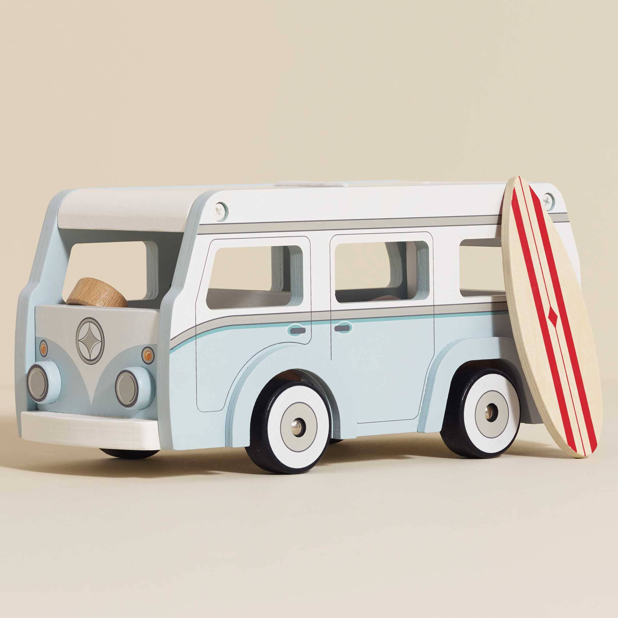 Wooden toy van with a surfboard on a beige background