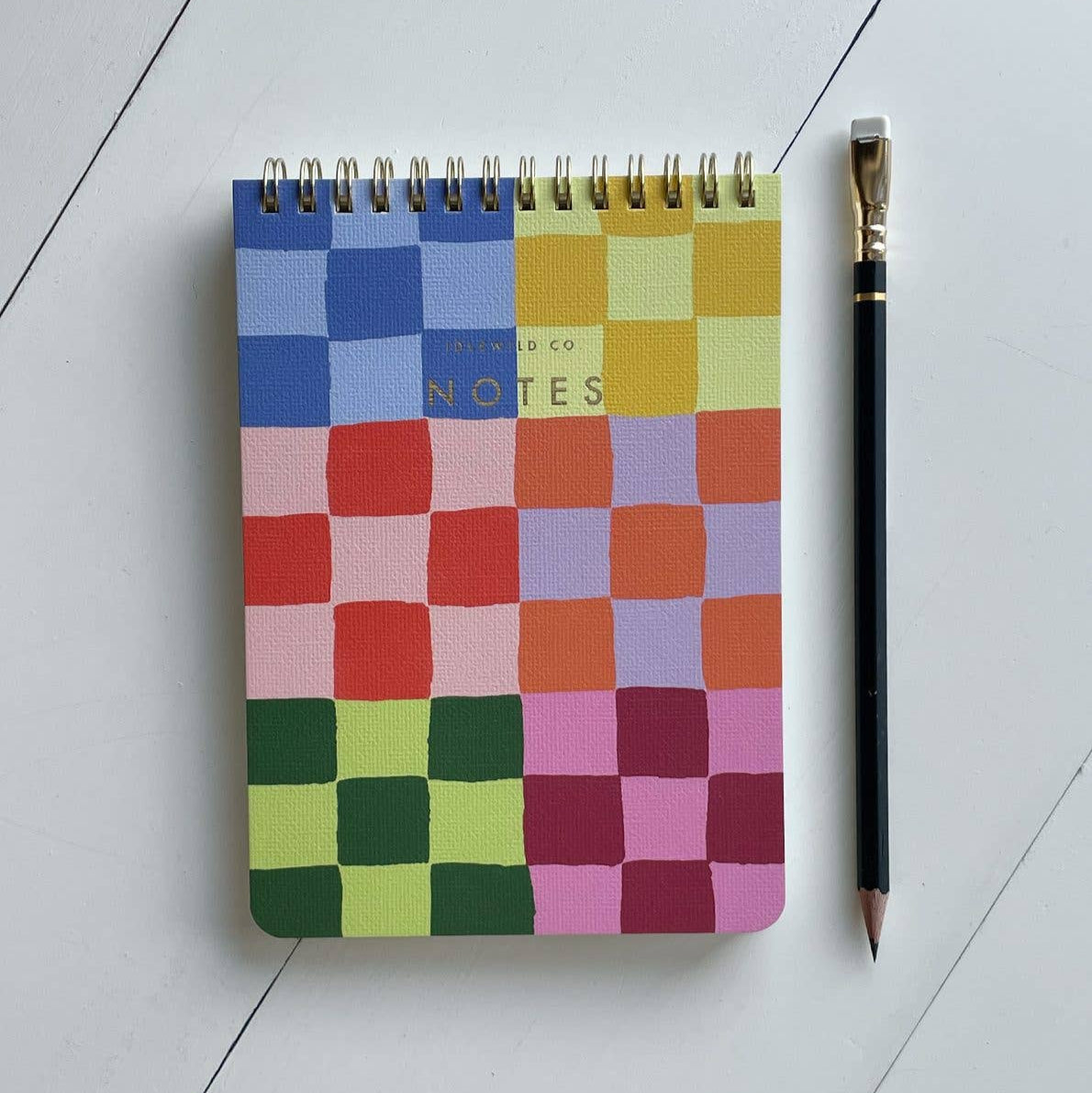Colorful checkered notebook with a pen on a light gray surface
