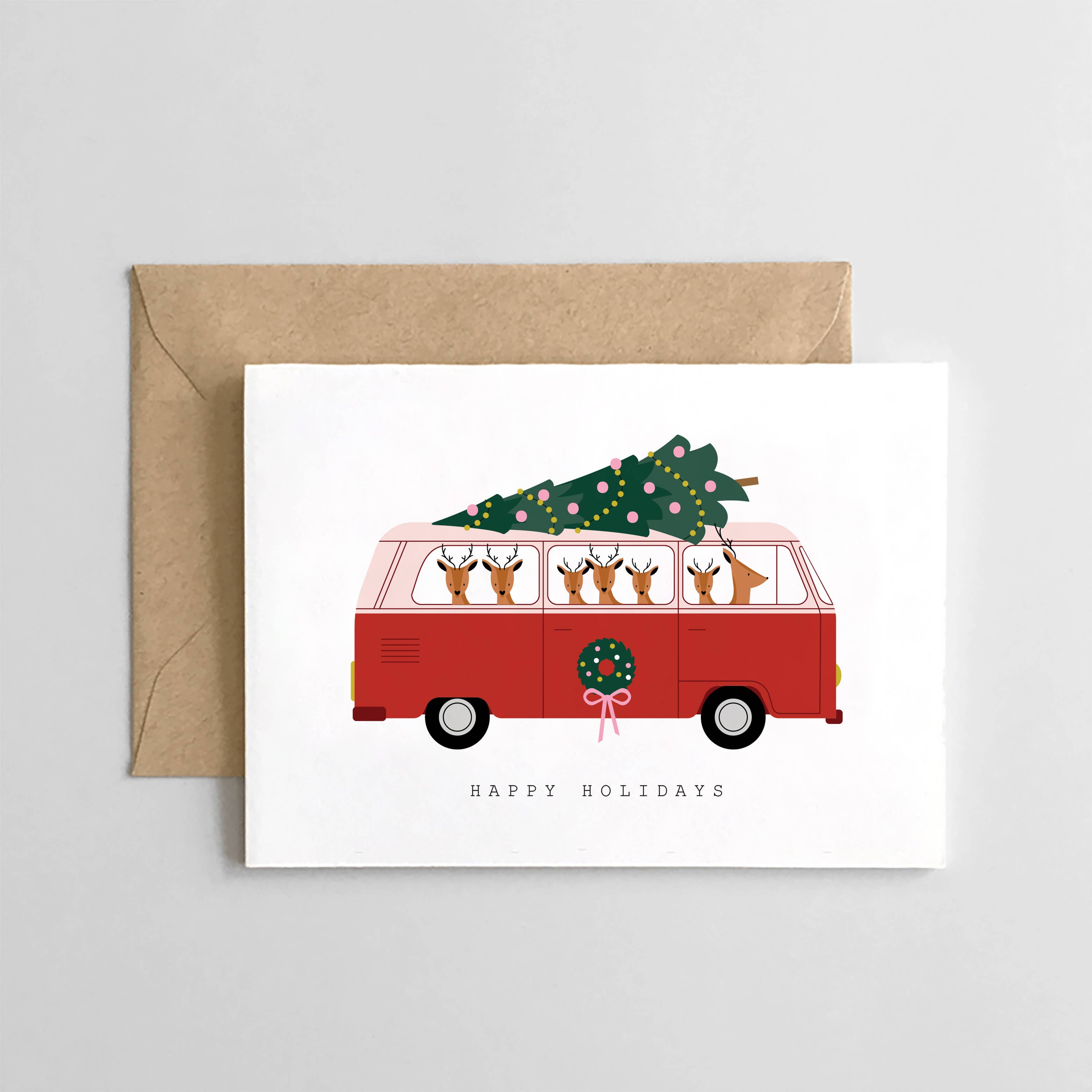 Greeting card with a red van carrying a Christmas tree and 'Happy Holidays' text, with a brown envelope.