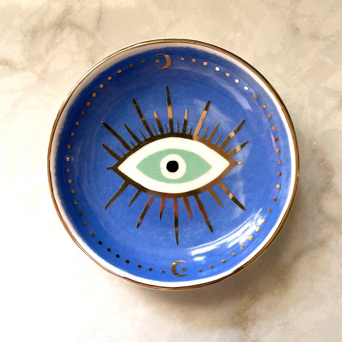 Blue ceramic dish with eye design on a marble surface
