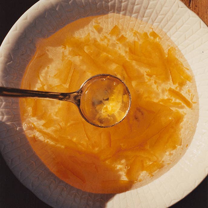 Spoonful of yellow jelly over a bowl of jelly