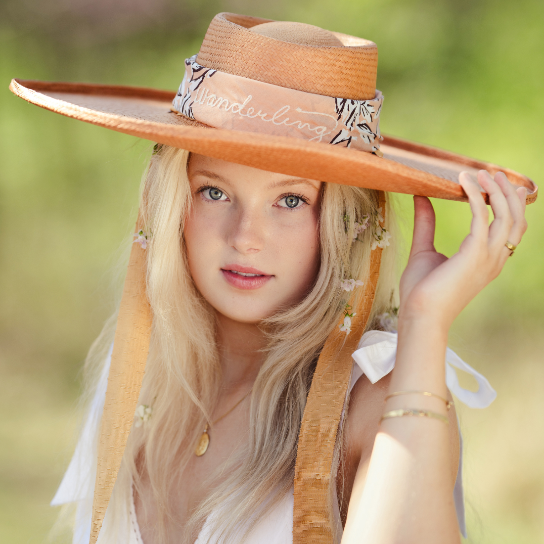 Woman wearing a wide-brimmed hat with 'Wunderlich' branding outdoors.