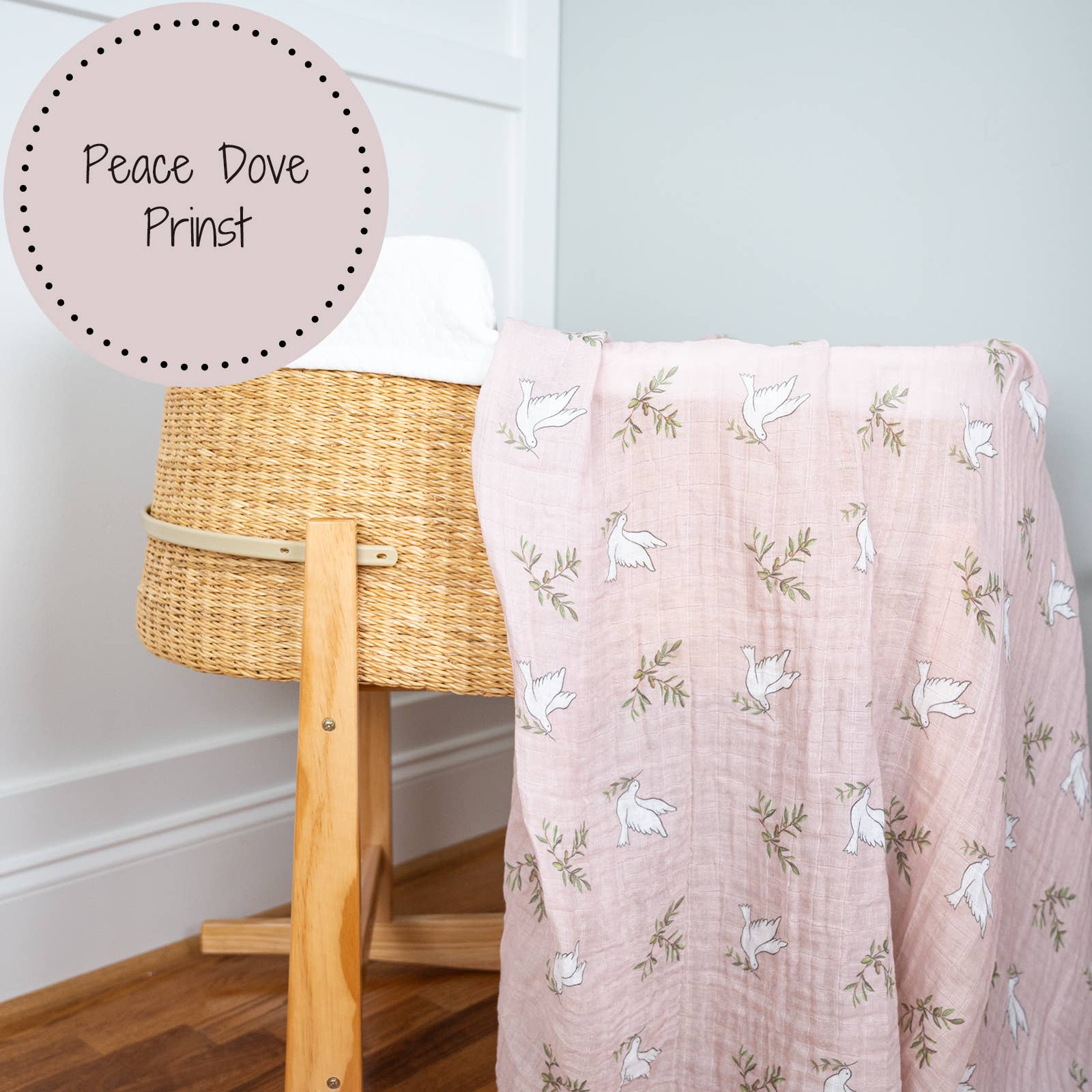 Pink baby blanket with white dove pattern draped over a wooden crib against a light blue wall.