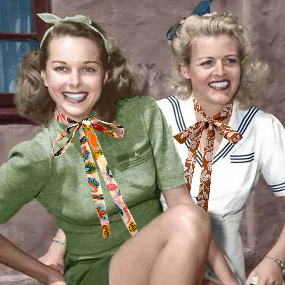 Two women sitting side by side with colorful scarves around their necks, against a plain background.