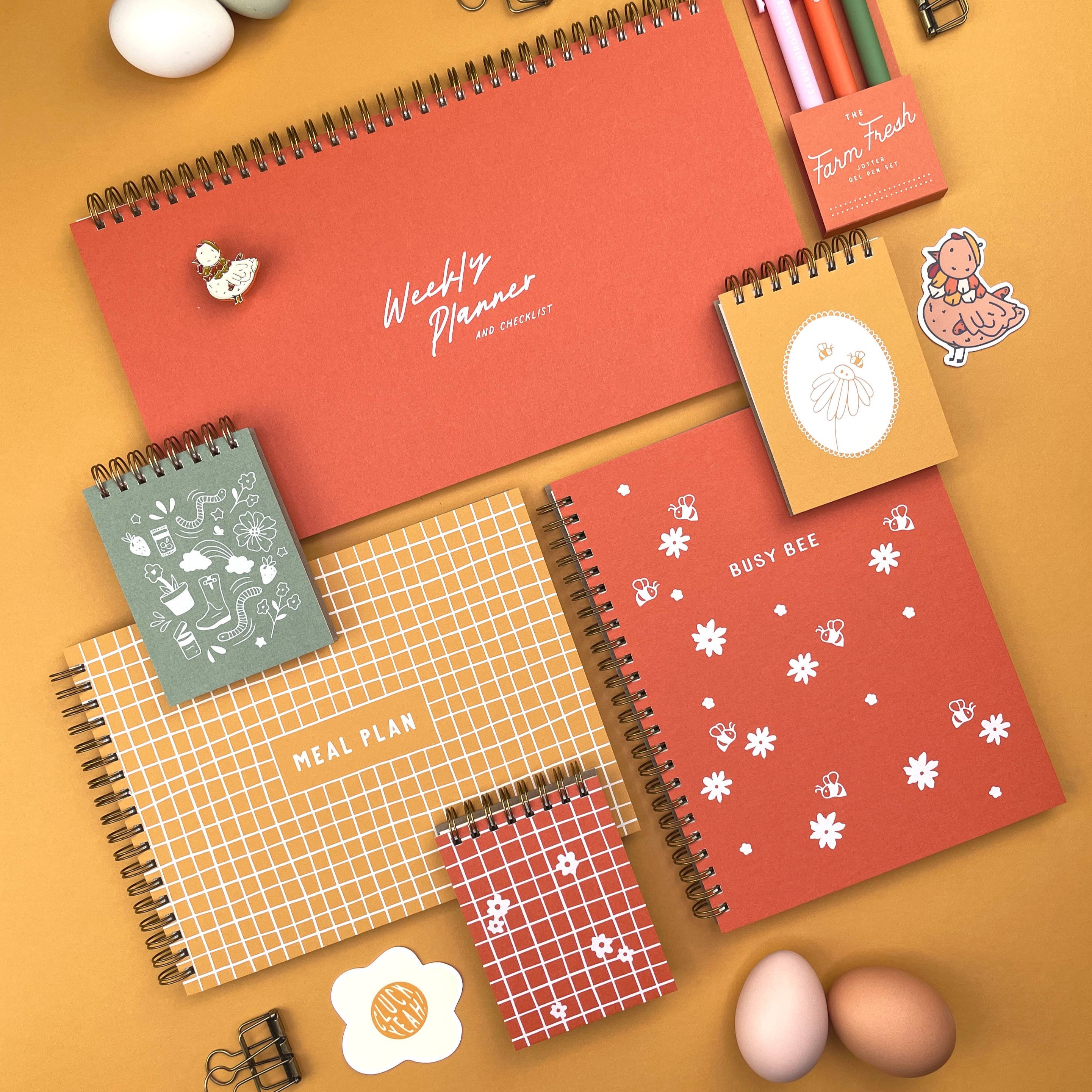 Collection of spiral-bound planners and stationery items on a yellow background