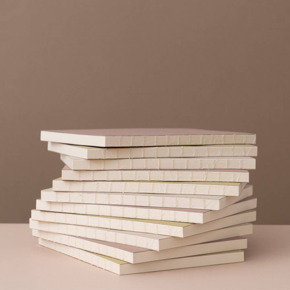 Stack of white books on a beige surface with a brown background