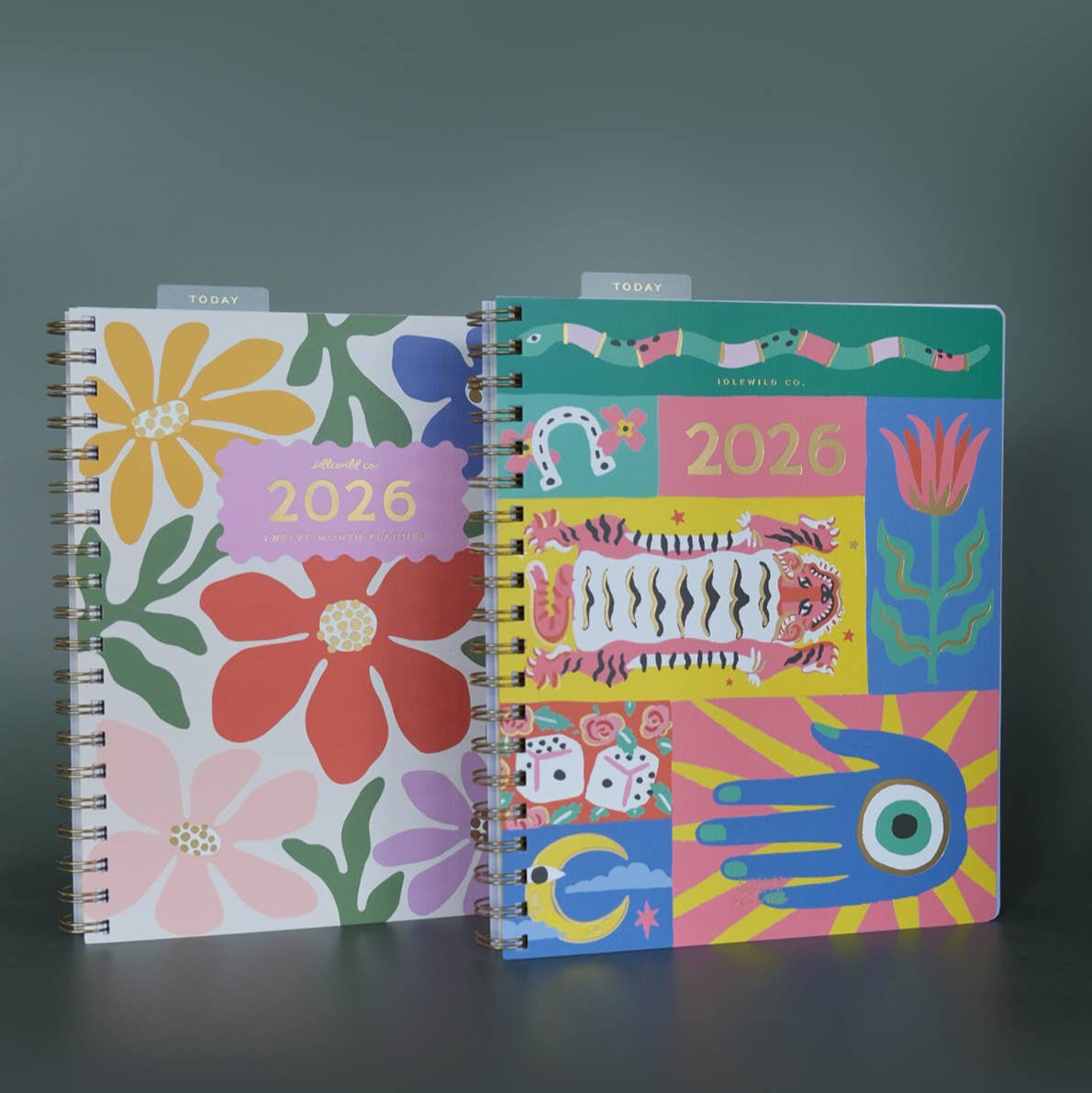 Two colorful planners with floral and abstract designs on a dark background