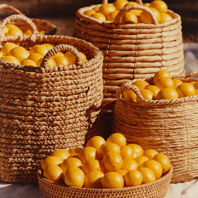 Wicker baskets filled with lemons on a wooden surface