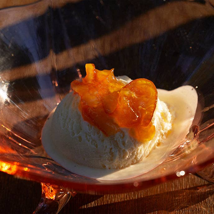 Ice cream with caramelized fruit on a clear glass plate