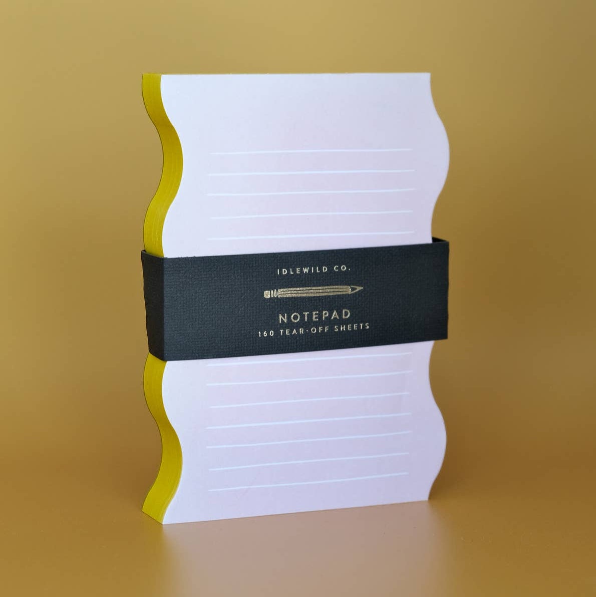 White notepad with black band and yellow edges on a gold background