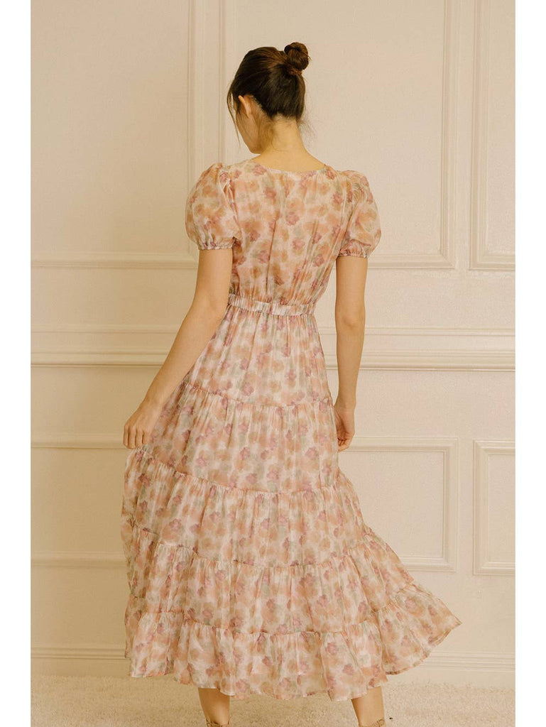 Water-painted floral ruffled midi dress. It displays a V neckline, short puffy sleeves, and a wrapped, ruched center. It has an upper torso peephole, high elastic cinched waist, and ruffled flowy midi bottom.