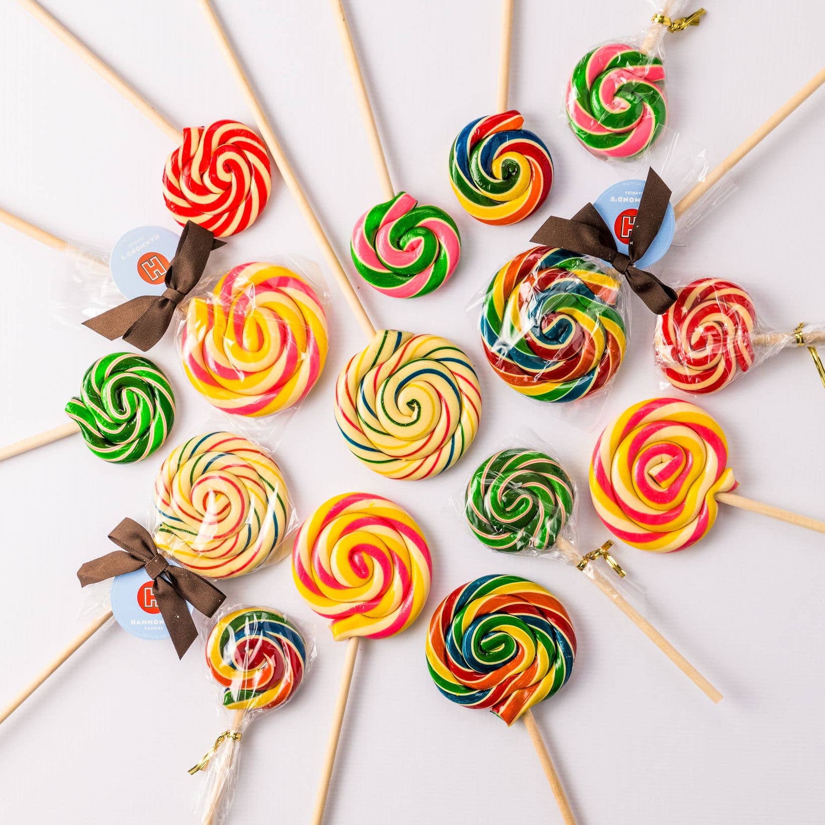 Colorful swirl lollipops on sticks arranged in a circular pattern on a light background.
