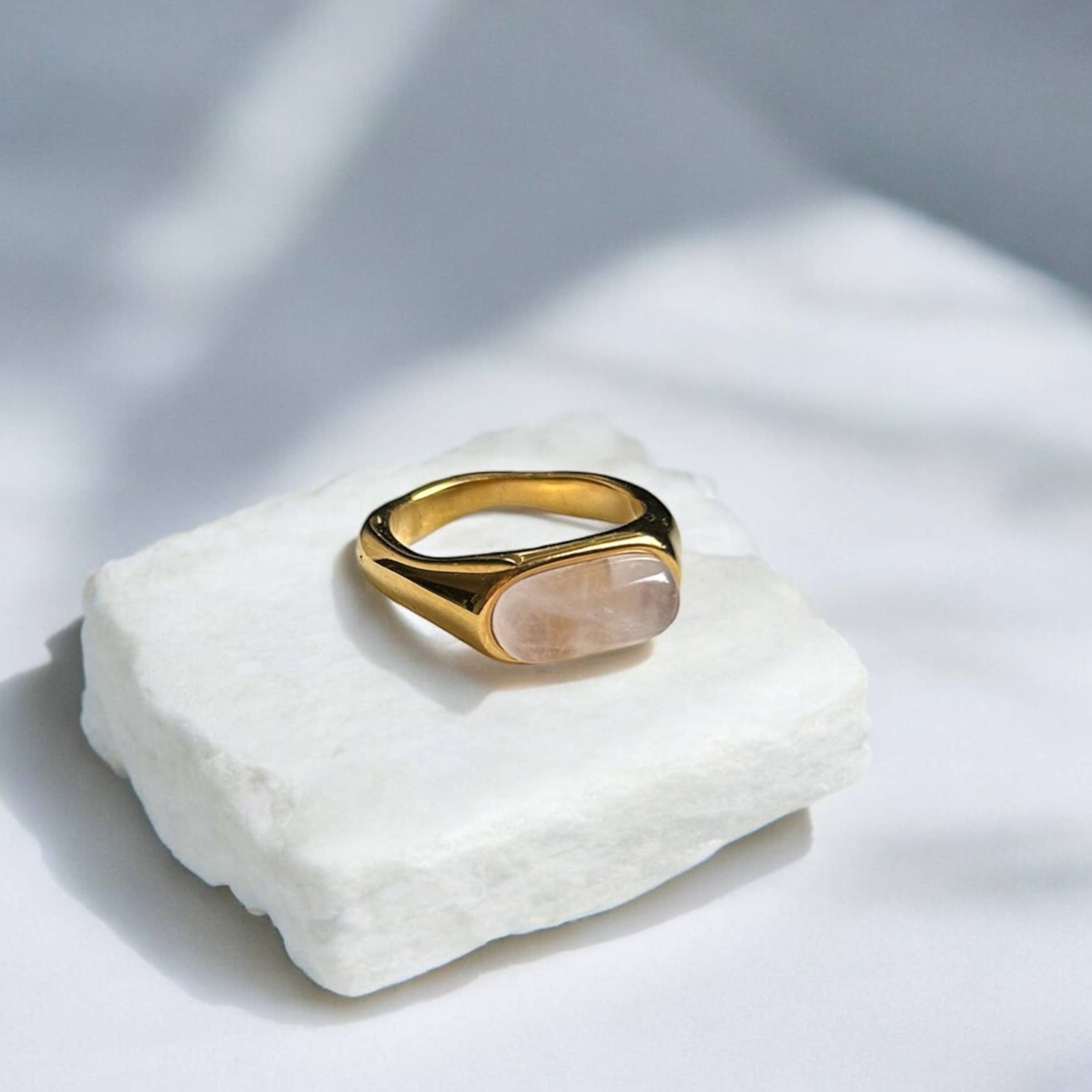 Gold ring on a white stone surface with soft shadows
