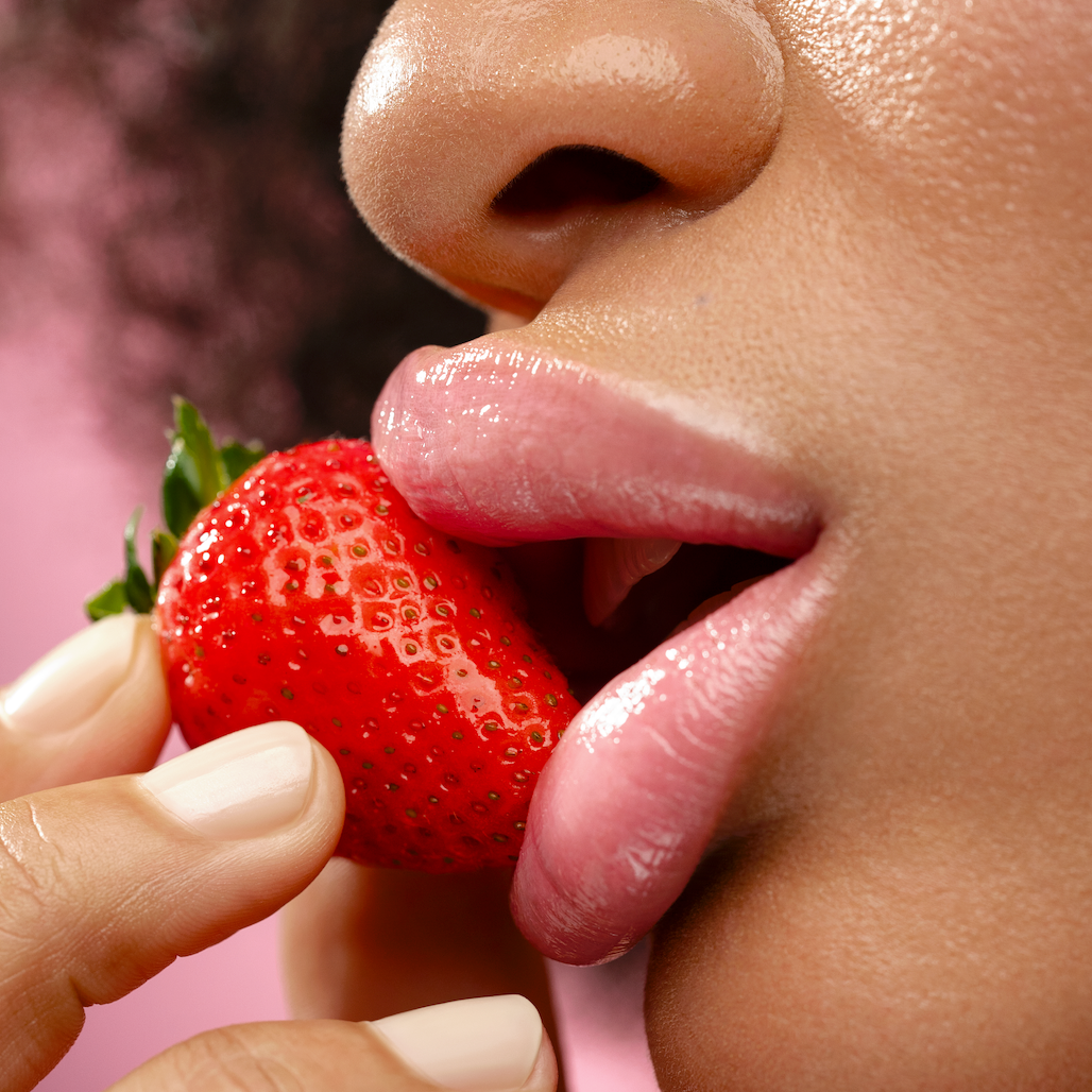 Close-up of a person biting into a strawberry with a blurred background