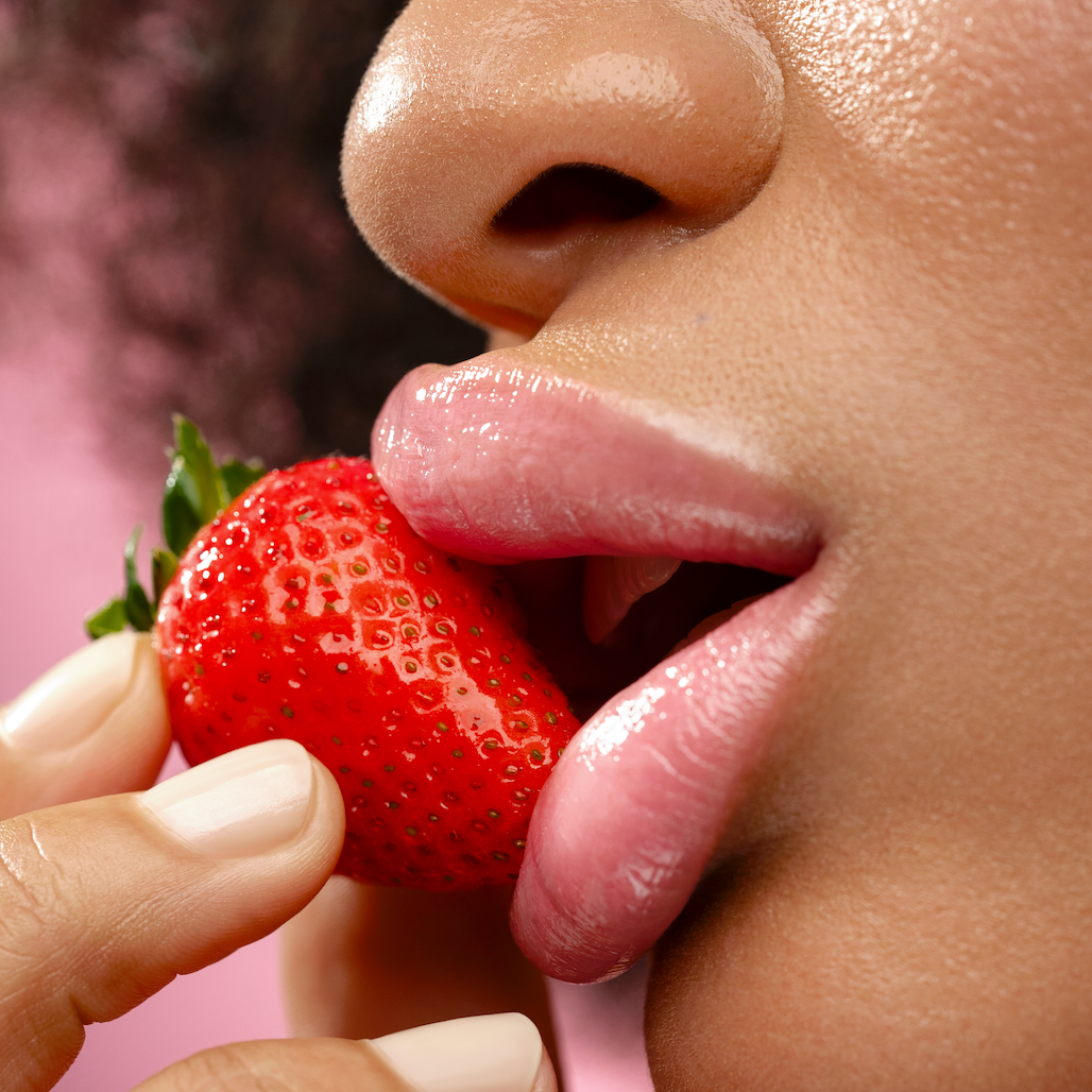 Close-up of a person biting into a strawberry with a blurred background