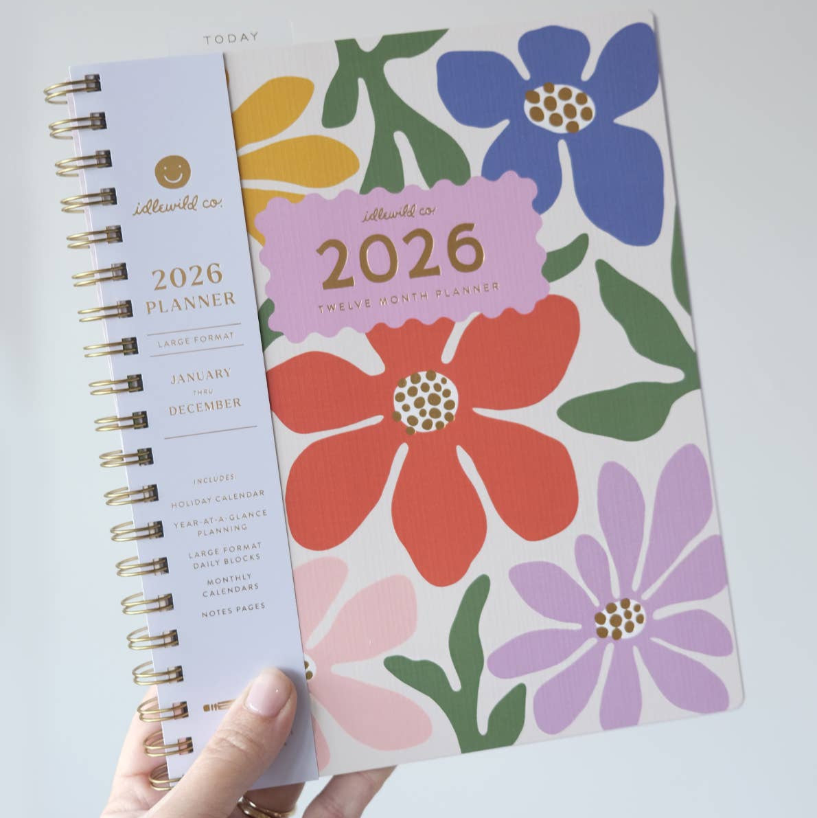 Floral 2026 planner held by a hand on a light gray background