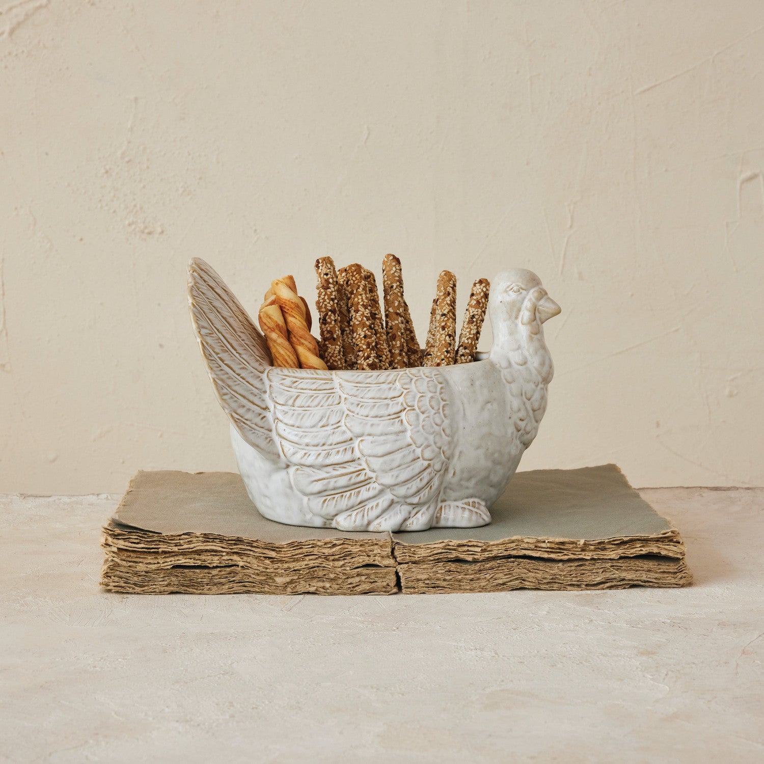 Decorative bird-shaped bread basket with bread sticks on a neutral background