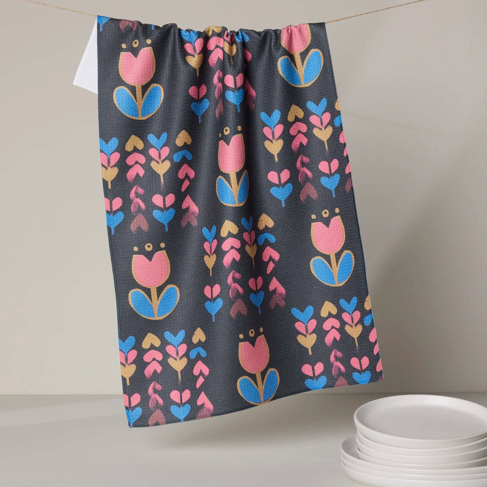 Floral patterned towel hanging on a line with plates below Tea Towel