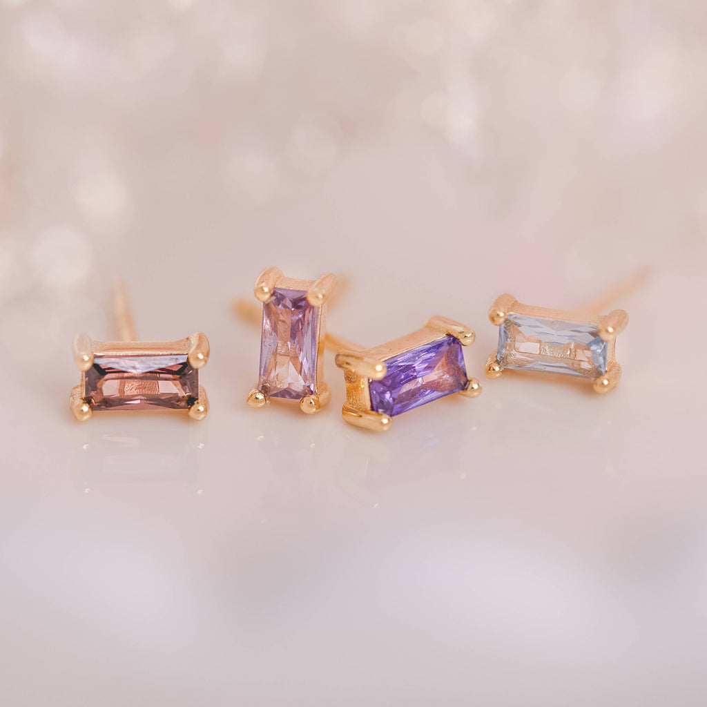  Birthstone Ombre Baguette Stud Earring Set, a collection of four stunning earrings crafted in 18k gold plated with an anti-tarnish coating. This set of stud earrings showcases the ombre effect, seamlessly blending hues from light to dark, creating a captivating visual representation of your birthstone's color spectrum. 