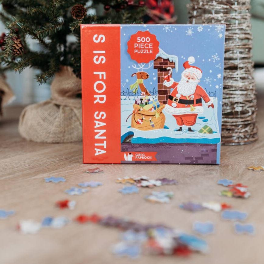 Celebrate the jolliest season with the 500-piece jigsaw puzzle illustrated by Greg Paprocki, the creator of Gibb Smith’s wildly popular Baby Lit alphabet series. Featuring an adorable Santa in Greg’s signature vintage style, this playful puzzle is perfect for all ages. Gather around a table with family or friends or piece it together by yourself!