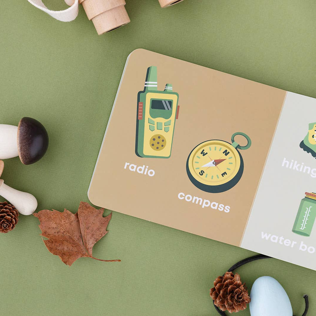 Notebook with stickers of a radio and compass on a green surface with mushrooms and leaves.