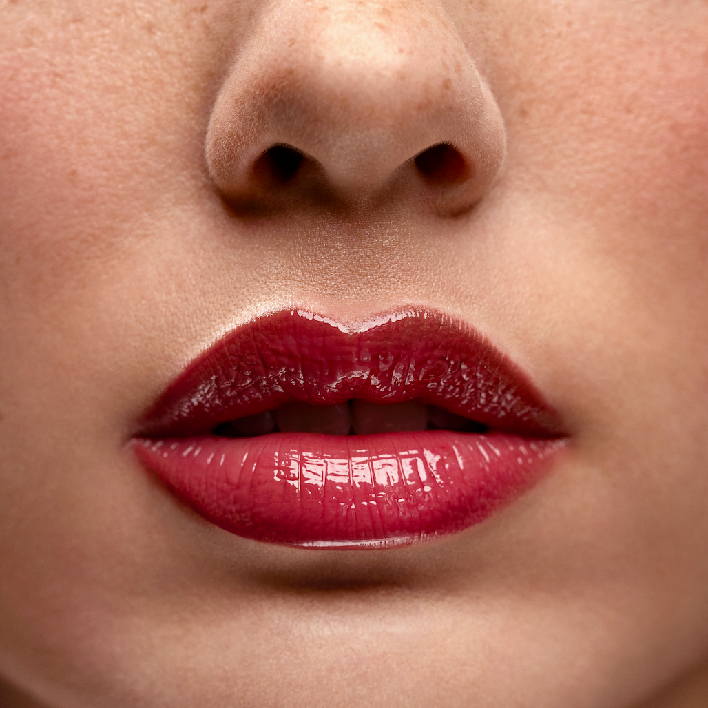 Close-up of a person's lips with red lipstick on a blurred background