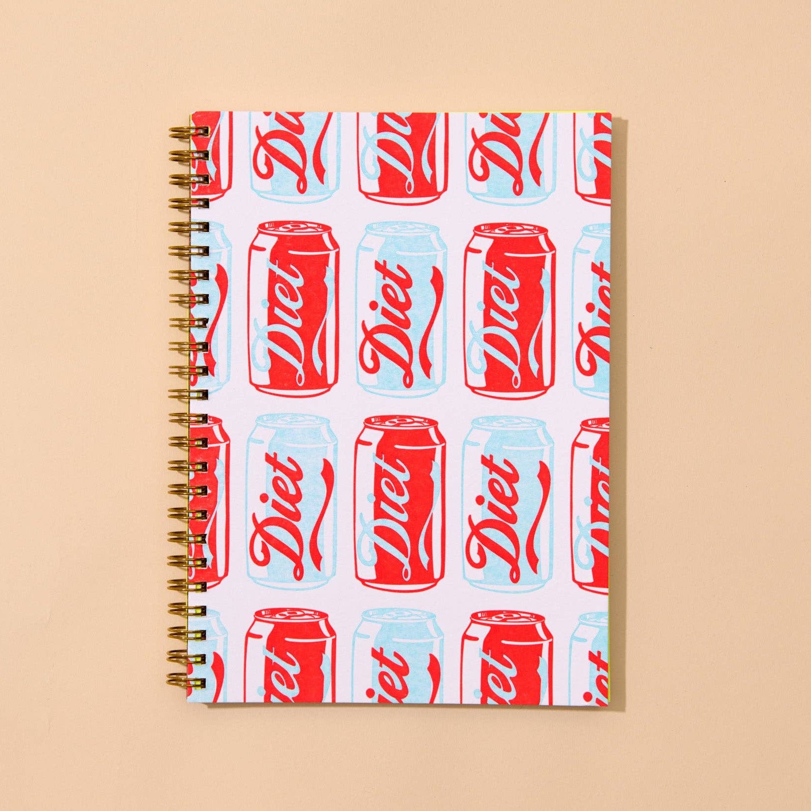 Notebook with Diet Coke can pattern on a beige background