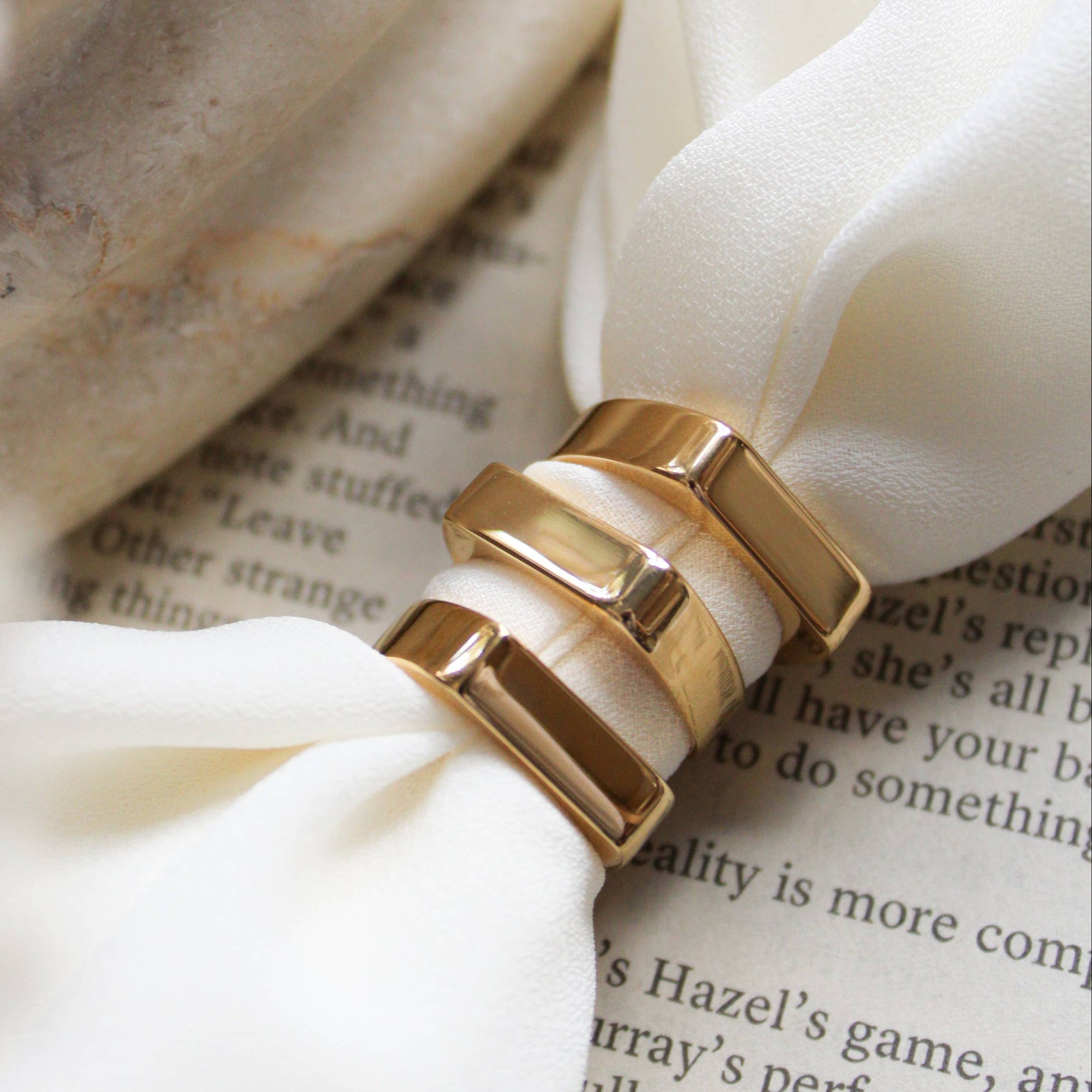 Gold ring with white stone on a white fabric background