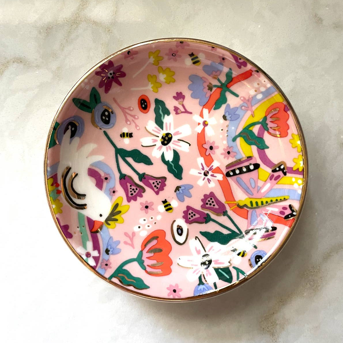 Decorative plate with colorful floral and abstract designs on a marble surface