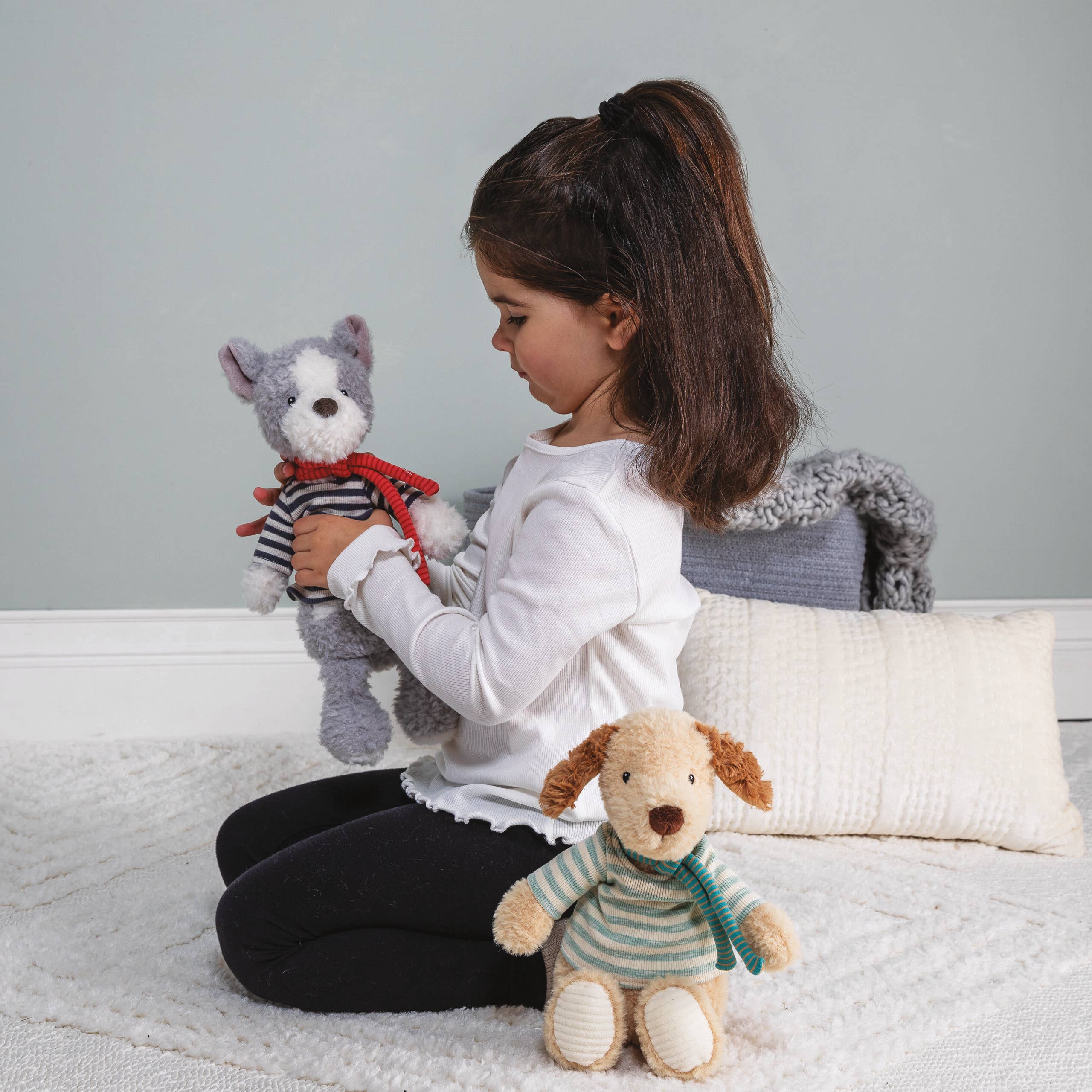 Child playing with stuffed animals on a bed