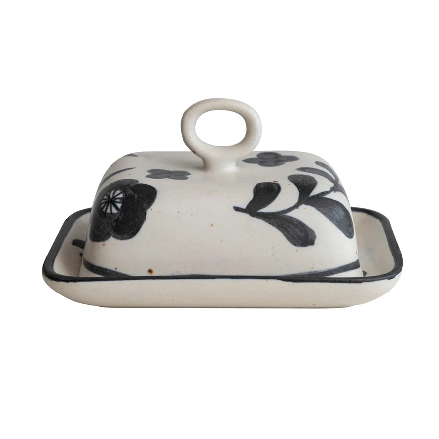 Keep your butter fresh and fly with this hand-painted stoneware butter dish. With its beautiful floral design and a dynamic duo of matte black and cream colors, this butter keeper will be sure to make heads turn! Who knew that butter storage could be so stylish? Butter up, buttercup!     Dimensions   6-3/4"L x 5-3/4"W x 4"H      Material  100% Stoneware  Matte Black & Cream Color Speckled