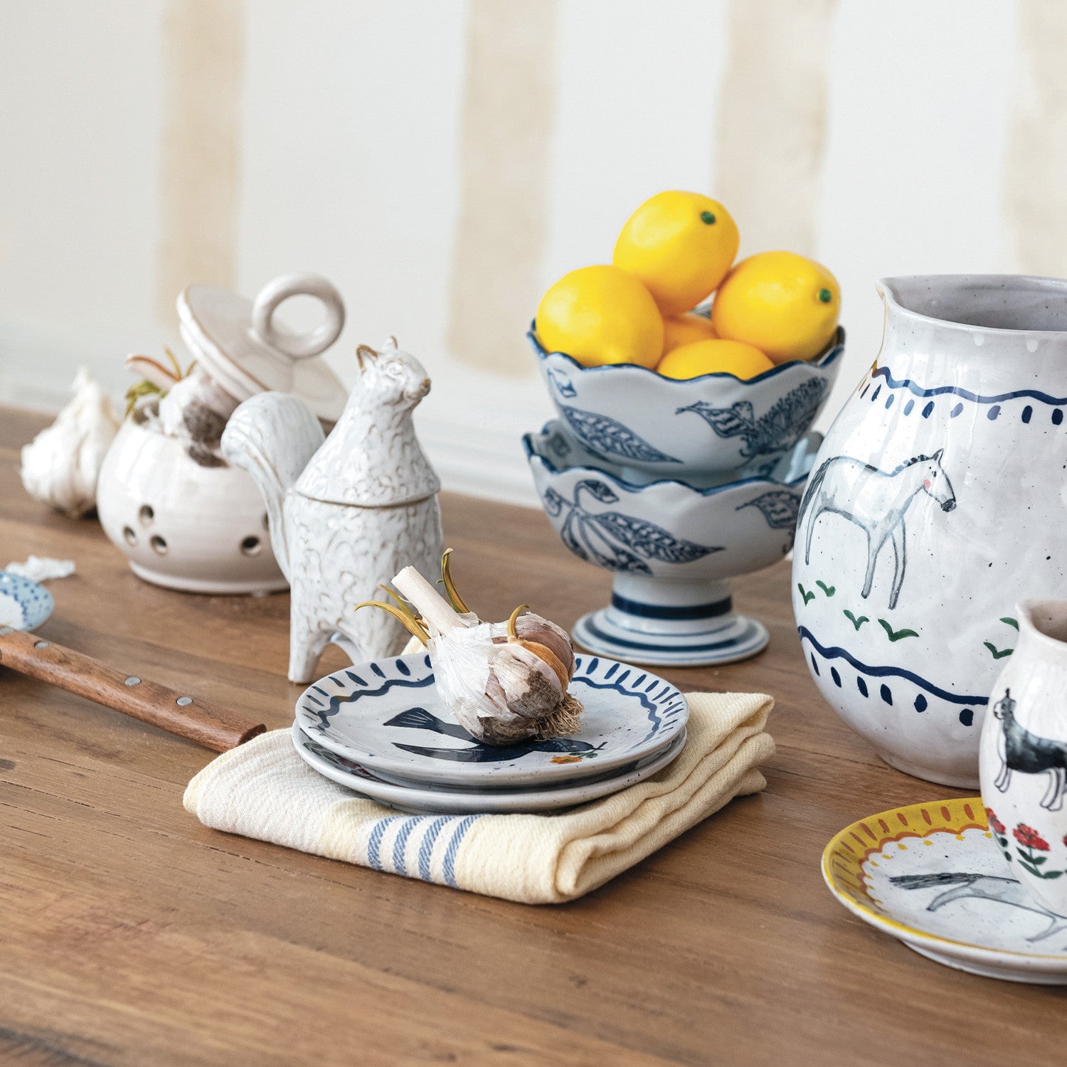 Decorative ceramic items including a teapot, bowls, and plates on a wooden surface.