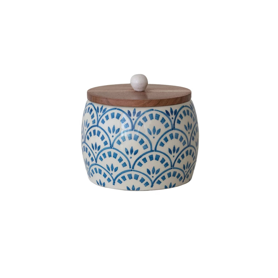 Brighten up your kitchen with this Hand-Painted Stoneware Canister topped with a warm Acacia Wood Lid! Perfect for storing everything from coffee to cookies, its unique hand-painted design adds a splash of personality to your countertop. The natural wood lid keeps contents fresh while giving your space a cozy, playful vibe. Storage has never looked this fun! 5-3/4" Round x 5-1/4"H
