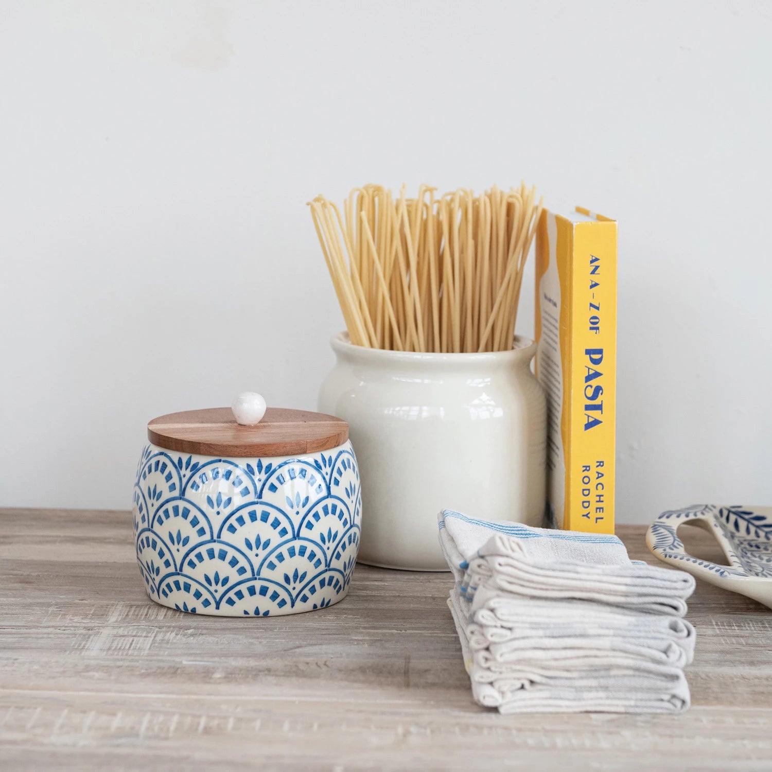 Brighten up your kitchen with this Hand-Painted Stoneware Canister topped with a warm Acacia Wood Lid! Perfect for storing everything from coffee to cookies, its unique hand-painted design adds a splash of personality to your countertop. The natural wood lid keeps contents fresh while giving your space a cozy, playful vibe. Storage has never looked this fun! 6-1/2" Round x 7"H