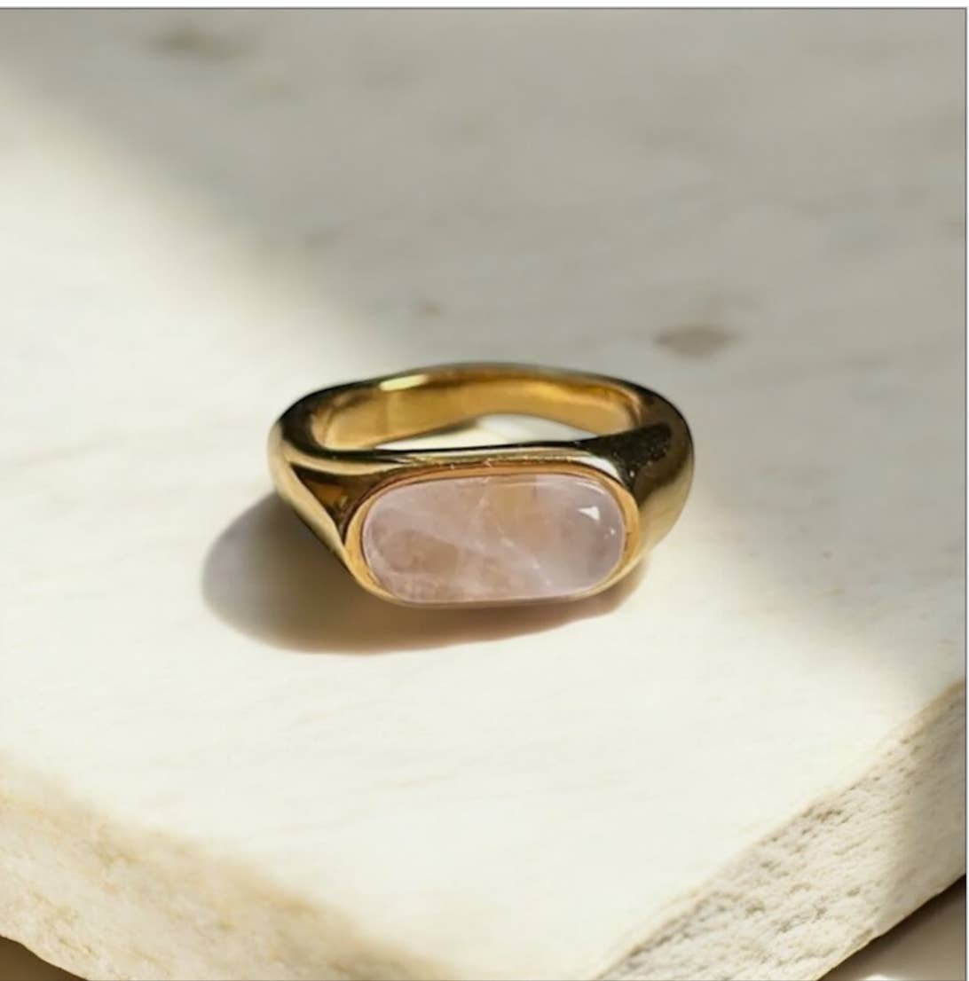 Gold ring with a pink stone on a light stone surface