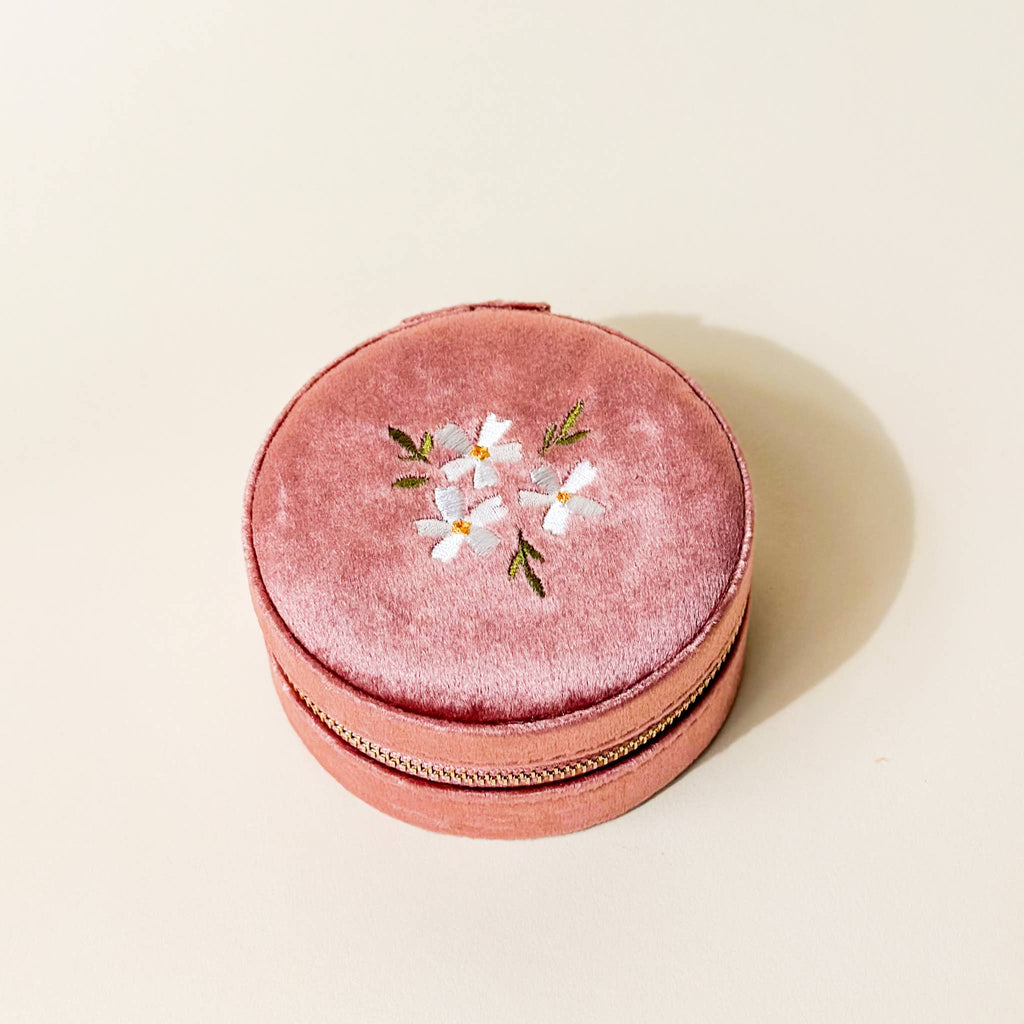 Your new adorable solution for keeping accessories safe and organized on the go! On the outside, this case features a stunning floral embroidered lid and gleaming gold zipper hardware. Inside, you'll find 5 slots for rings or earrings, an interior lid pouch, and open storage space for larger pieces.

Details:

Dimensions: 3” Round x 1.75” Thick
WARNING: Cancer and Reproductive Harm - www.P65Warnings.ca.gov