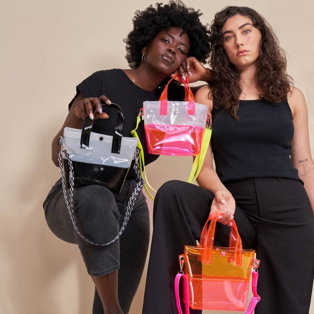 Miss your jelly sandals? This is your new favorite bag! Keep everything inside with a snap. The black and white translucent vinyl handle bag has a black snap closure and is detailed with silver metal grommets. It's available with or without the detachable black and white checkered 1" strap