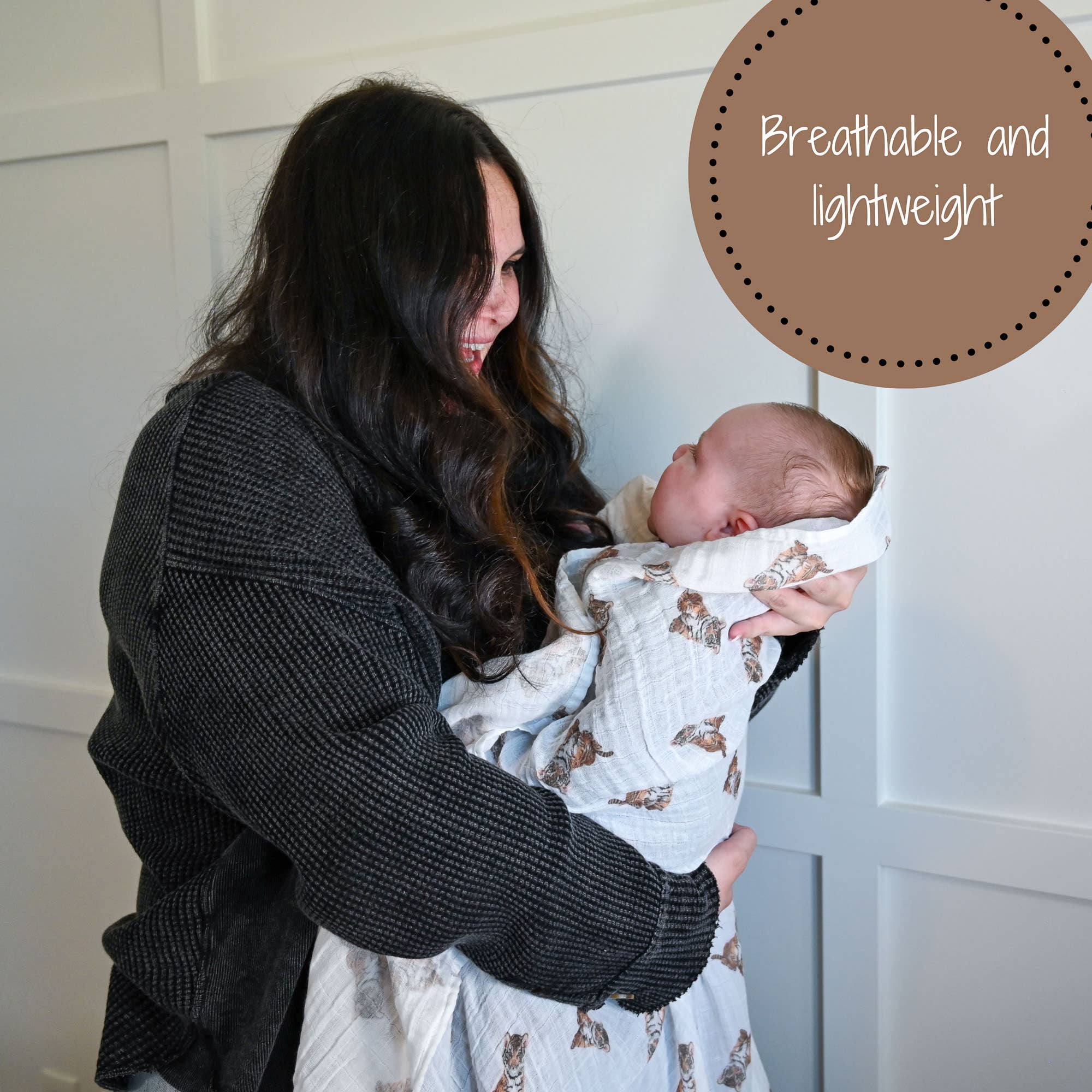 Woman holding a baby wrapped in a blanket with text 'Breathable and lightweight' on a wooden panel background.