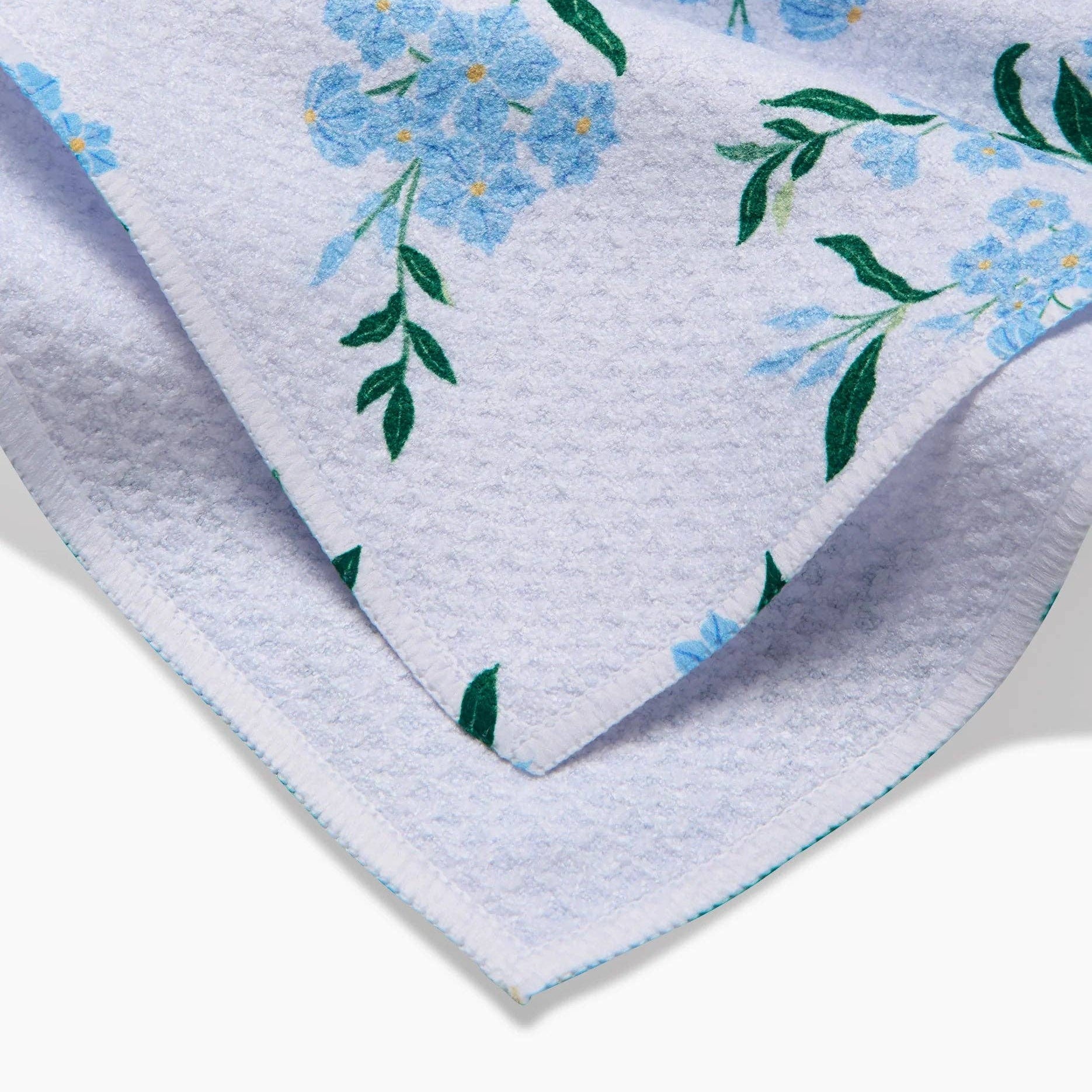 Floral-patterned fabric with blue flowers and green leaves on a white background