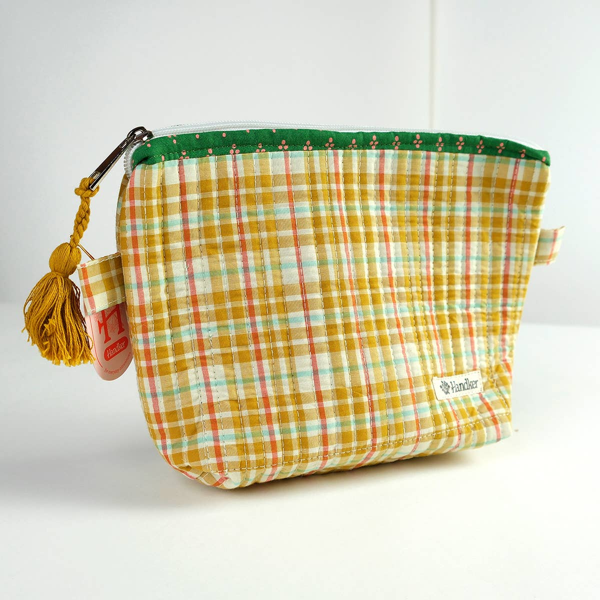 Plaid pouch with green zipper and yellow tassel on a white background