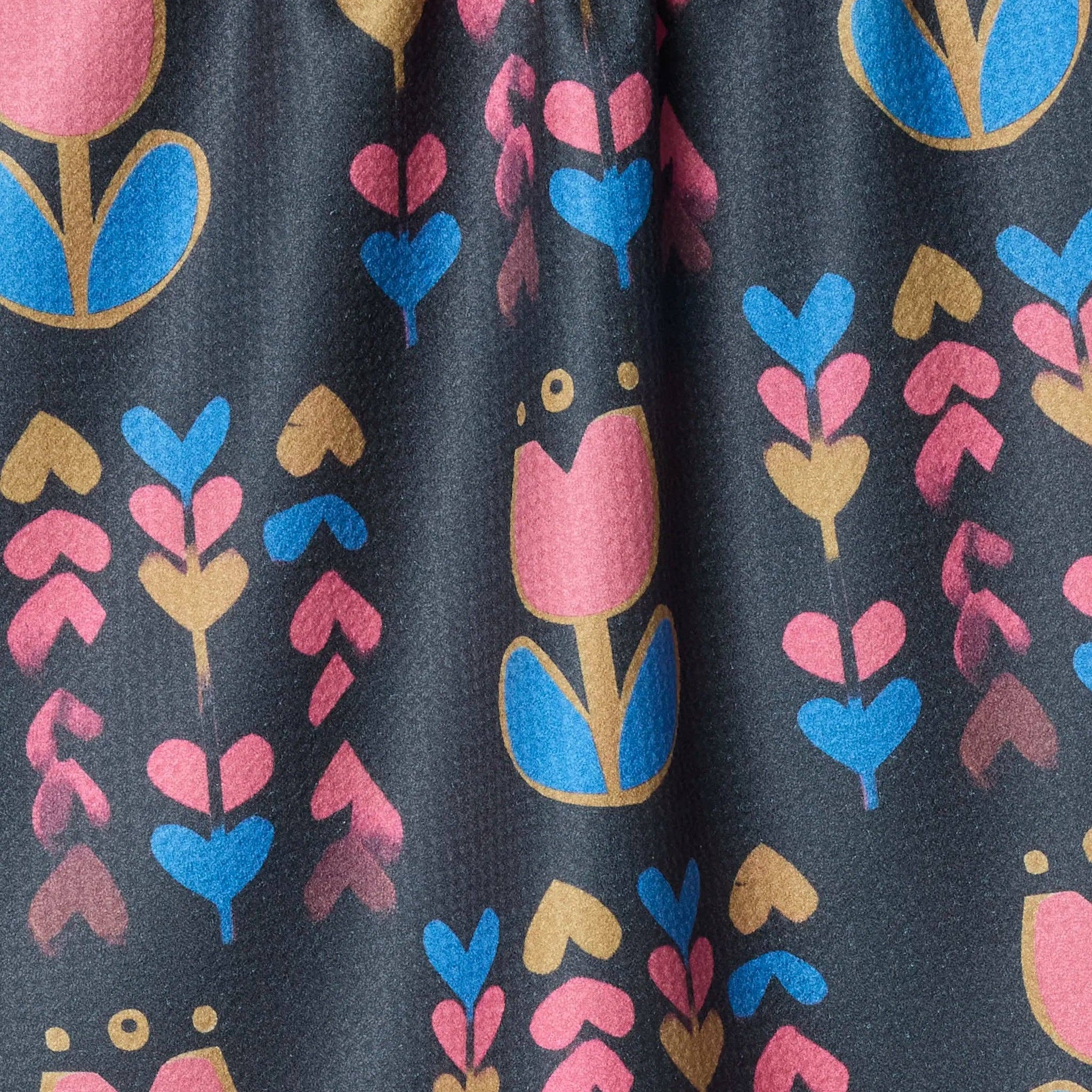 Close-up of fabric with colorful floral pattern on a dark background Tea Towel