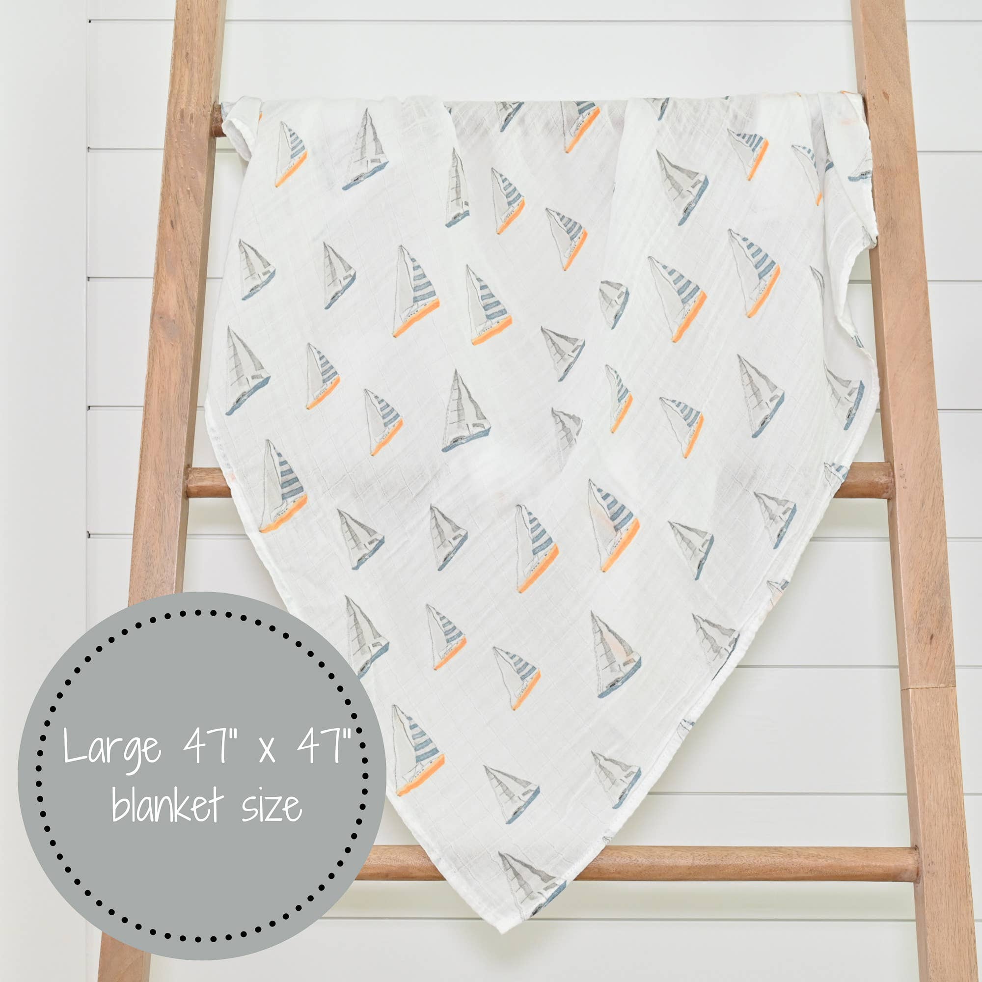 Blanket with sailboat pattern draped over a wooden ladder on a white background
