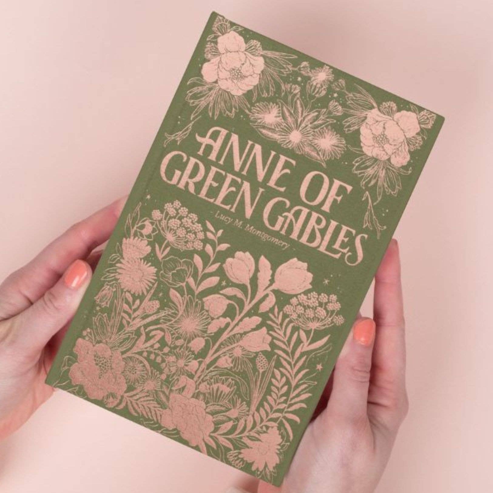 Book titled 'Anne of Green Gables' held by a person with a floral design on the cover.