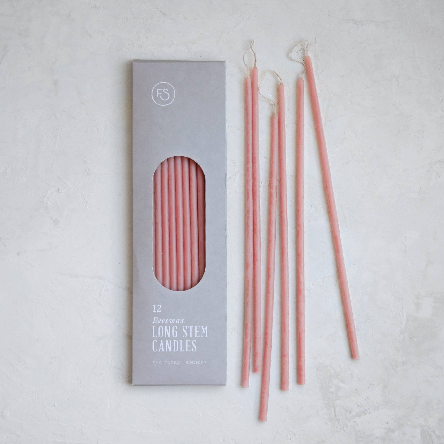Set of pink candles with packaging on a light gray background