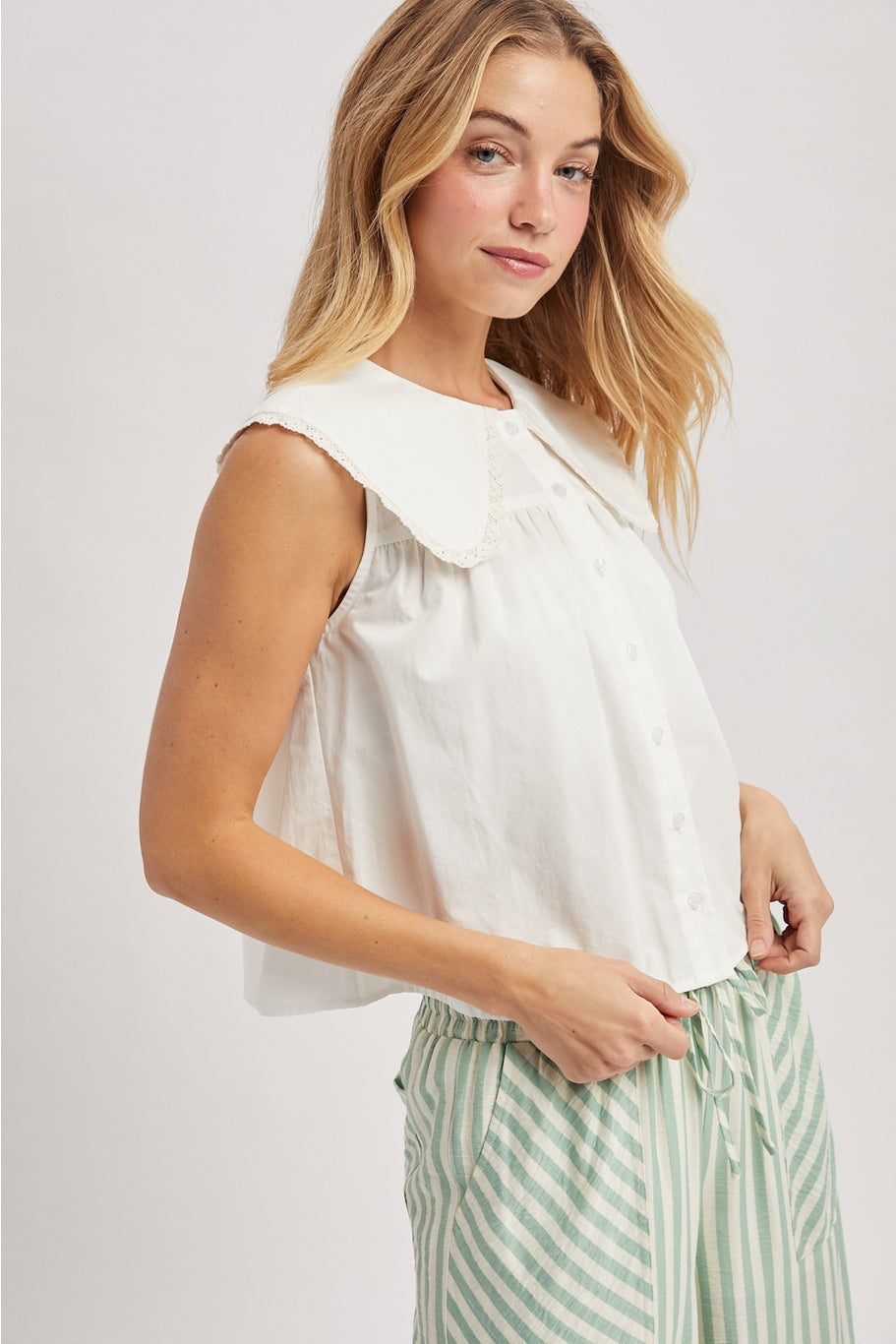White sleeveless blouse with buttons and a large lace edged pan collar. 