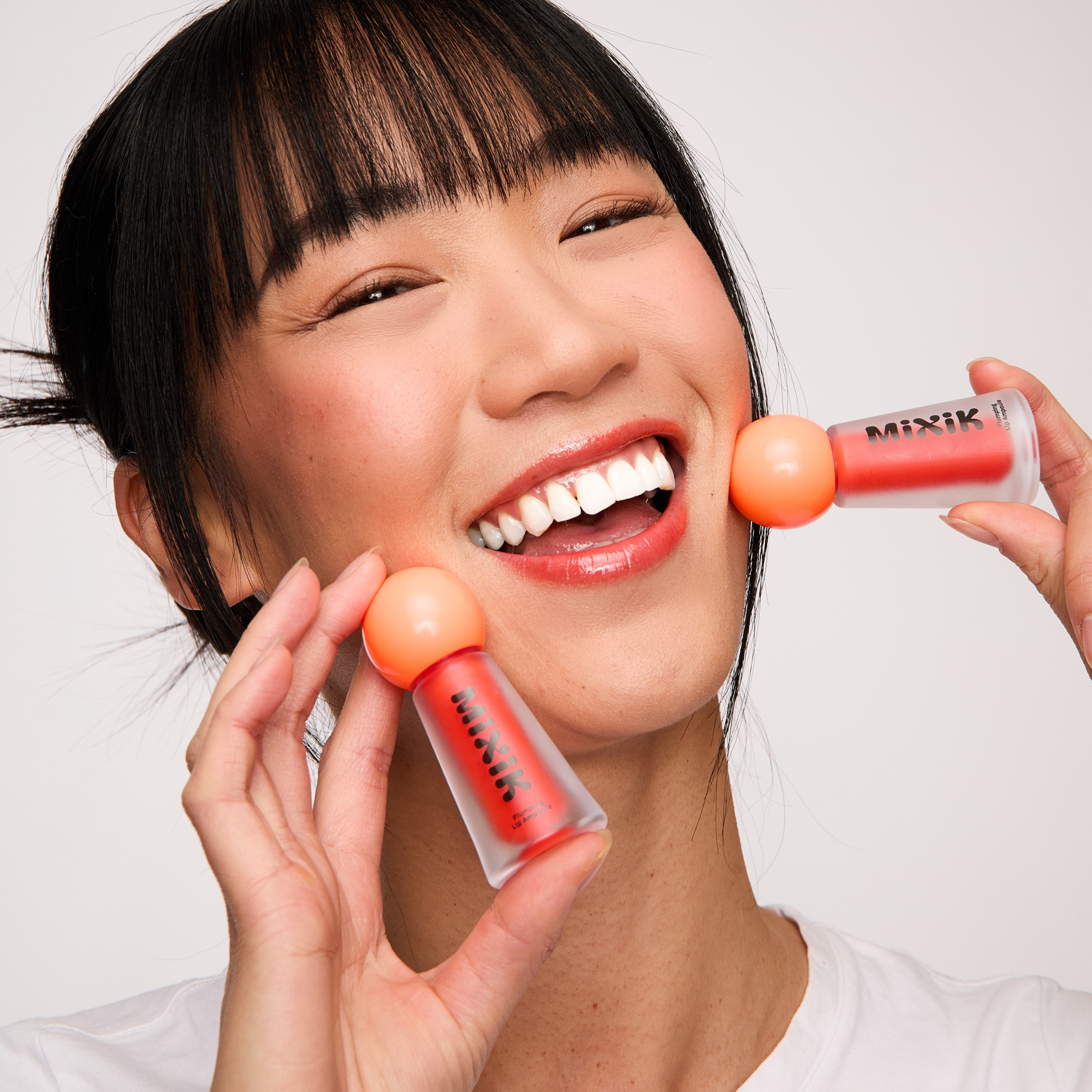 Woman holding two small orange and clear containers with a white background