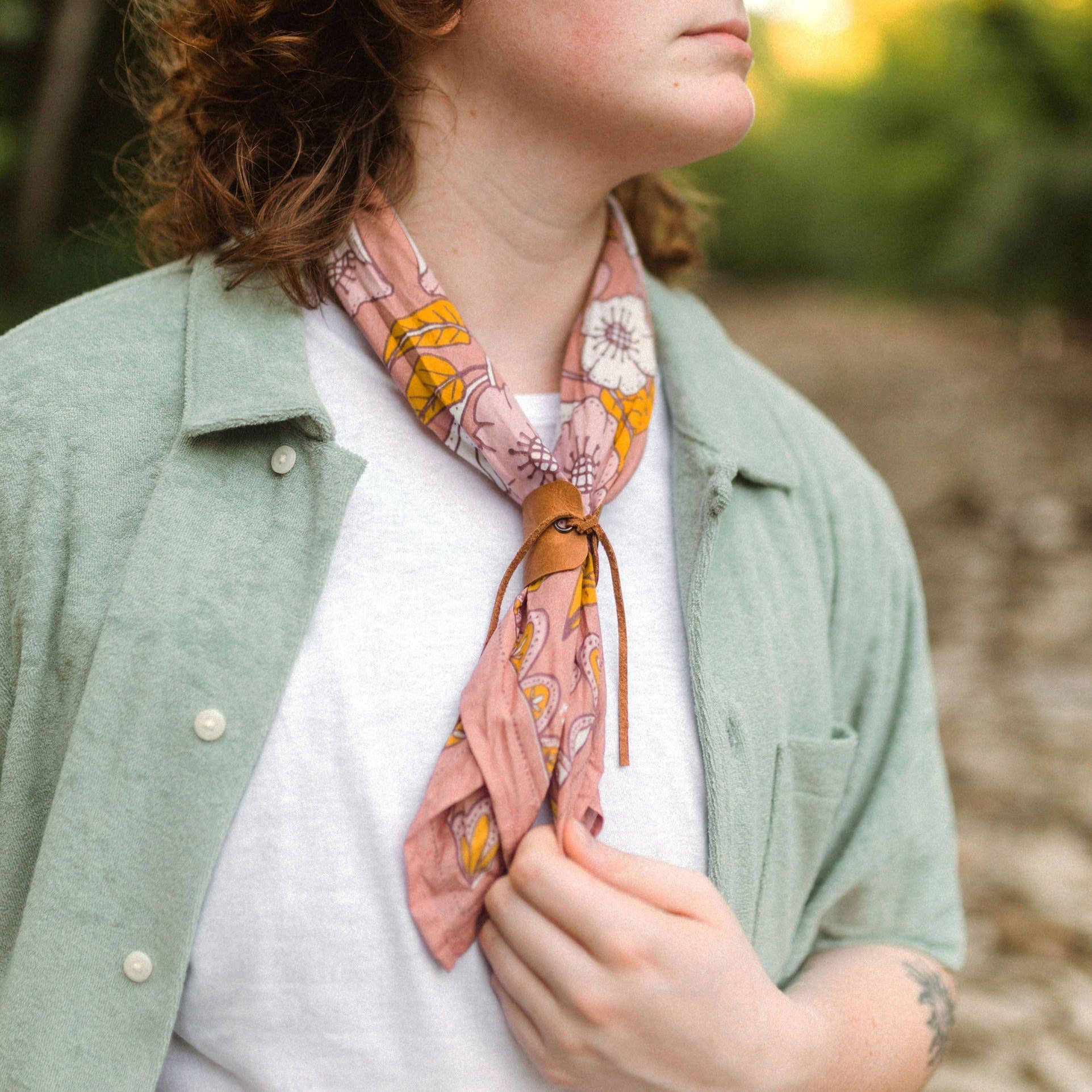 Person wearing a floral scarf with a blurred natural background