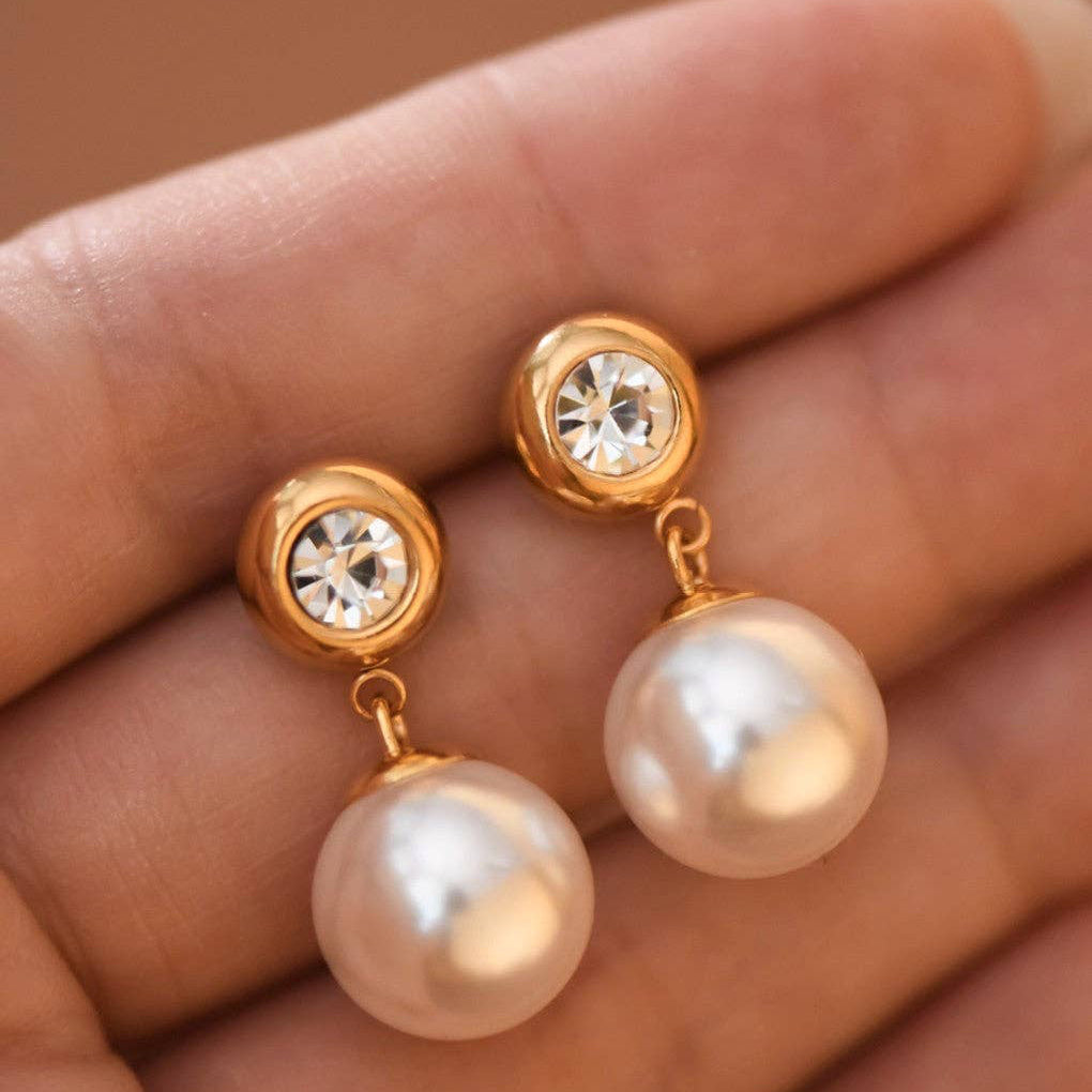 Elevate your everyday look with these elegant 18K gold-dipped stainless steel earrings featuring lustrous pearl drops. Measuring approximately 1" in length, they offer a timeless aesthetic that complements any style. Crafted for durability, these earrings are hypoallergenic, waterproof, and tarnish-resistant—perfect for sensitive skin and active lifestyles. To maintain their radiant finish, avoid prolonged contact with lotions, perfumes, and cleaning products. A versatile essential.
