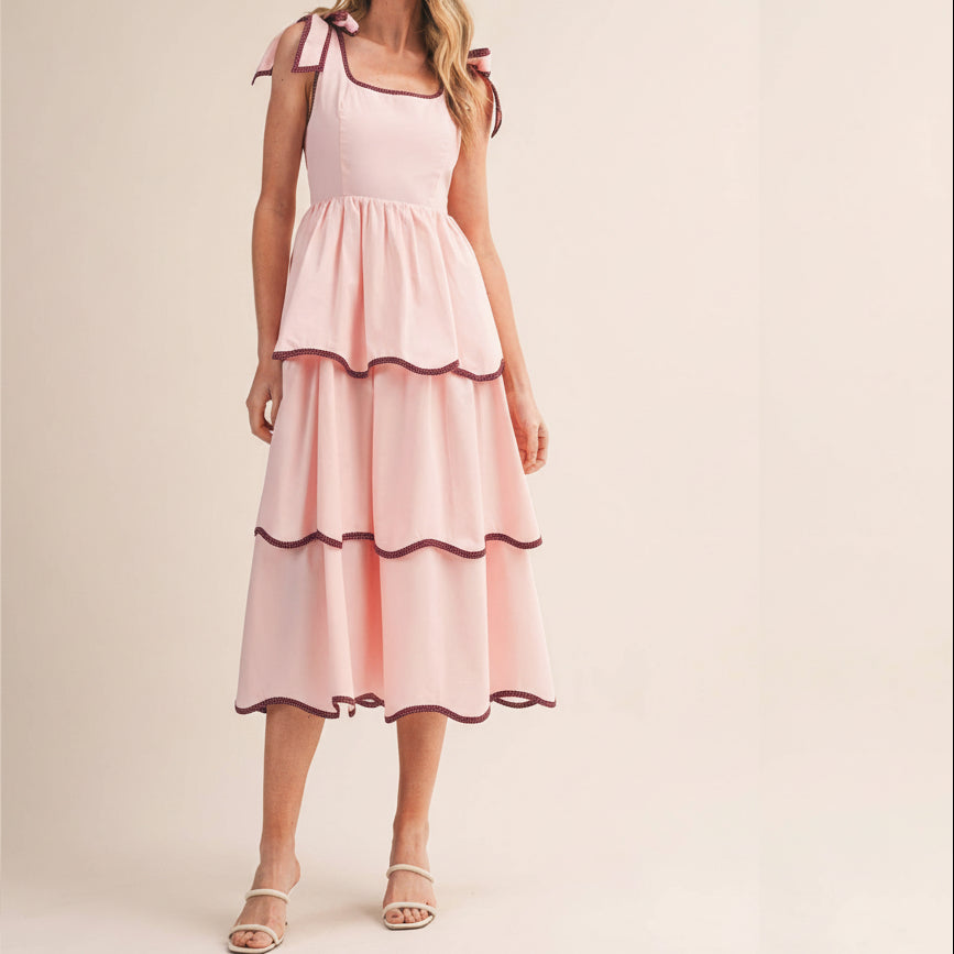 This charming contrast binding tiered midi dress celebrates your unique style with thoughtful details designed to make you feel confident and beautiful. The square neckline and tying straps feature elegant contrast binding that frames your shoulders perfectly, while the fitted bodice with smocked elastic back provides comfortable support throughout your day. Layers of tiered skirt create graceful movement and dimension, each adorned with contrast binding for a polished, intentional look.